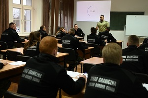 Funkcjonariusz z komisji egzaminacyjnej oraz słuchacze szkolenia podstawowego podczas egzaminu praktycznego 