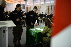 Funkcjonariuszka wydające karty egzaminaacyjne słuchaczom szkolenia podstawowego przed egzaminem teoretycznym 